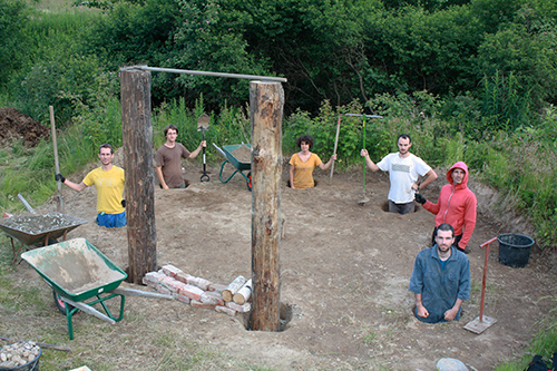 volunteers standing in the holes for the structure of the round house
